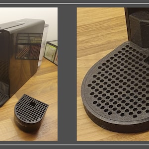 Op de afbeelding: Een zwarte koffiemachine met een druipbak en een aparte druipbakstandaard. De koffiemachine heeft een waterreservoir en een capsulehouder.