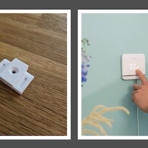 Op de afbeelding: Een witte, wandgemonteerde thermostaat met een digitaal display dat 22 graden Celsius aangeeft. Een persoon gebruikt een smartphone om de thermostaat te bedienen. De thermostaat is aangesloten op een stopcontact.