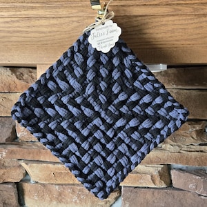May include: A black and blue woven pot holder with a tag that reads "Handmade by Julie's Loom" and includes a website and social media handle.