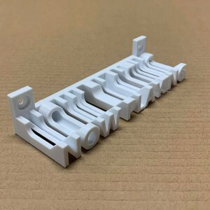 May include: White wall-mounted organiser with the word "NOW PLANNING" printed on it. The organiser has multiple slots for holding items.