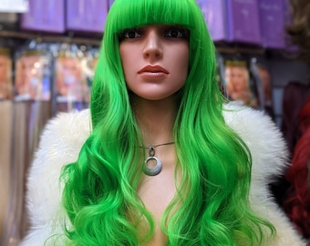 May include: A long, bright green wig with a fringe. The wig is styled in loose waves and is worn on a mannequin head.