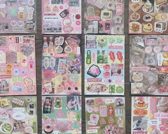 May include: A collection of decorative stickers with a pastel pink and white color scheme. The stickers feature various food items like cakes, desserts, and drinks, along with Japanese text and cute illustrations.