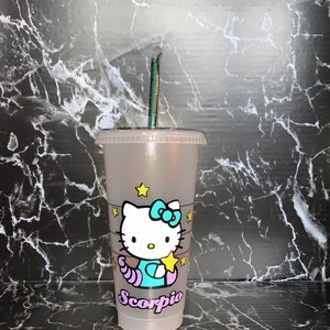 May include: A clear plastic reusable cup with a Hello Kitty design featuring a blue and purple scorpion with stars. The cup has the word "Scorpio" written on it.