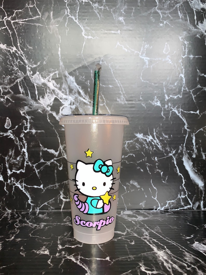 May include: A clear plastic reusable cup with a Hello Kitty design featuring a blue and purple scorpion with stars. The cup has the word "Scorpio" written on it.