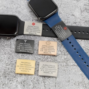 May include: Several medical alert tags with text are displayed near smartwatches. The tags are rectangular and feature names, medical conditions, and emergency contact information. The tags are in various colors, including silver, black, and tan.
