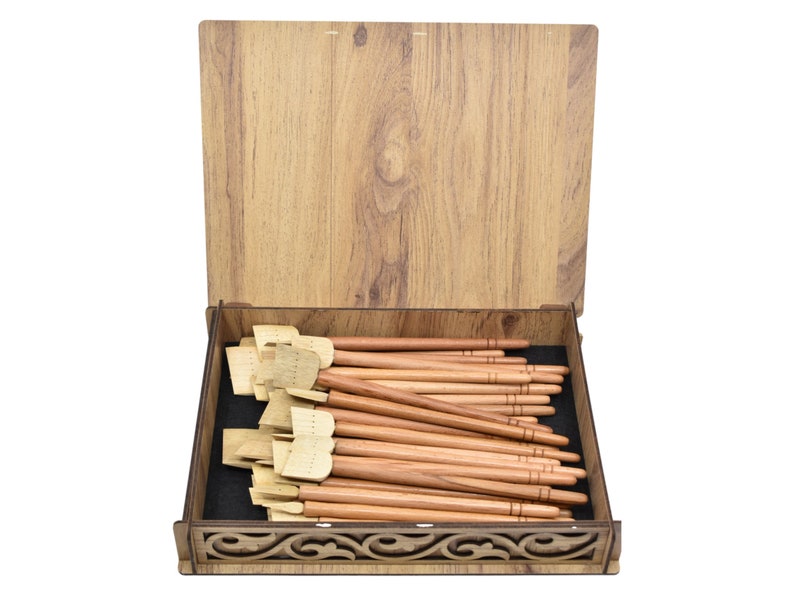 May include: A wooden box with a carved design on the front, containing a set of wooden calligraphy pens with a natural finish.