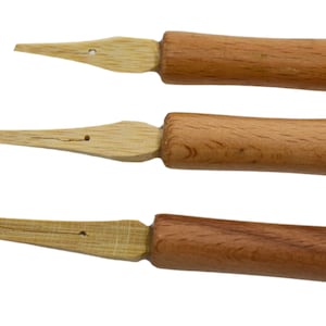 May include: Three wooden calligraphy nibs with a pointed tip and a wooden handle. The nibs are different sizes and have a natural wood finish.