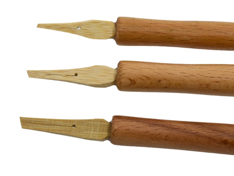 May include: Three wooden calligraphy nibs with a pointed tip and a wooden handle. The nibs are different sizes and have a natural wood finish.