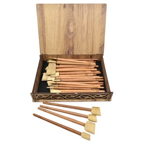 May include: A wooden box with a carved design on the lid, containing a set of 20 wooden calligraphy brushes with natural bristles. The box is open and the brushes are arranged neatly inside. Five additional brushes are shown outside the box.