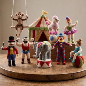 May include: A collection of needle-felted circus figures including a monkey on a swing, a striped tent, a poodle on a ball, a ballerina, a ringmaster, a strong person, an elephant on a pedestal, a clown, and a performer sitting on a ball.