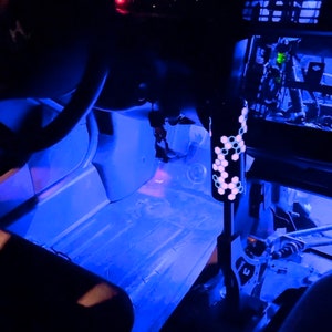 Puede incluir: El interior de un coche con luces LED azules que iluminan el suelo y el salpicadero. El salpicadero tiene un veloc&iacute;metro y otros indicadores. Se ve una palanca de cambios con un patr&oacute;n hexagonal.