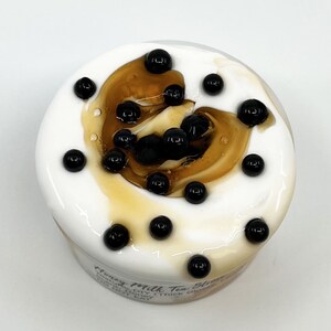 May include: A close-up of a white jar with a brown swirl and black boba pearls. The jar is labeled "Honey Milk Tea Slime" with the text "Handmade DIY (Thick Glossy No Heat".