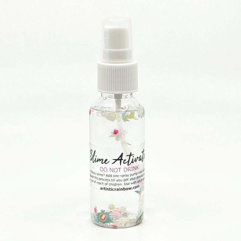 May include: A clear plastic bottle with a white spray nozzle filled with a clear liquid and colorful glitter. The bottle has a label that reads "Slime Activator" and "DO NOT DRINK". The label also includes the text "artisticrainbow.com".