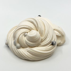 May include: White slime with silver and black beads. The slime is in a swirl pattern.