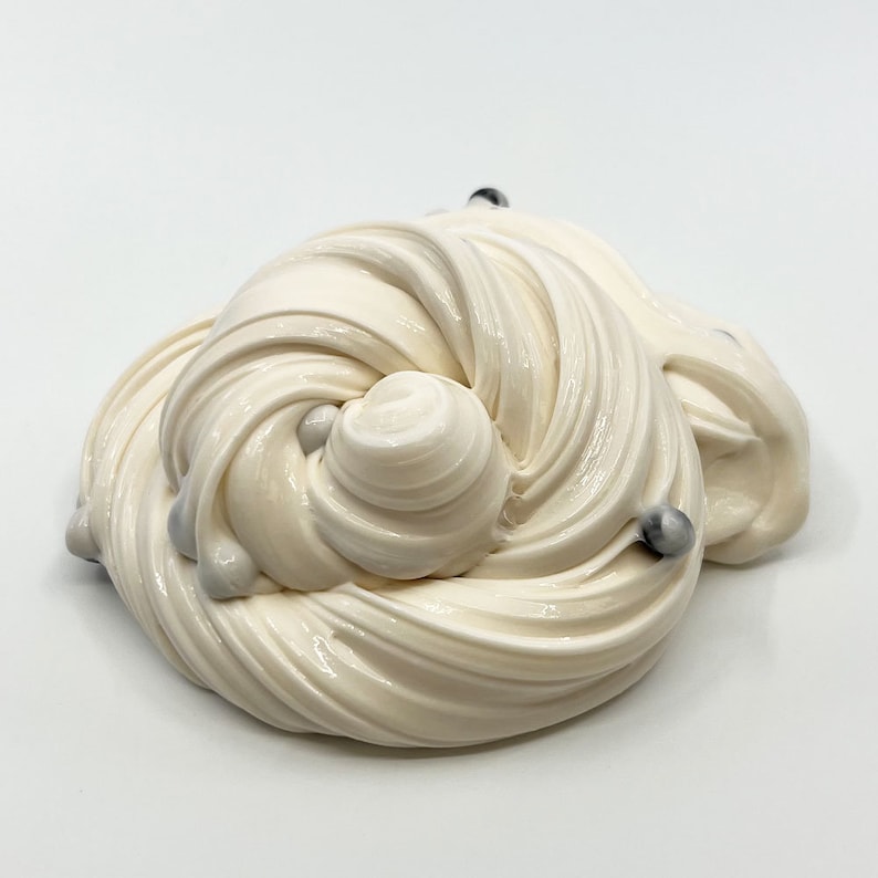 May include: White slime with silver and black beads. The slime is in a swirl pattern.