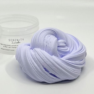 May include: A lavender-coloured slime in a clear container. The slime is soft and fluffy, and it has a calming scent. The container has a label that says "Serenity Lavender" and "Aromatherapy Slime".