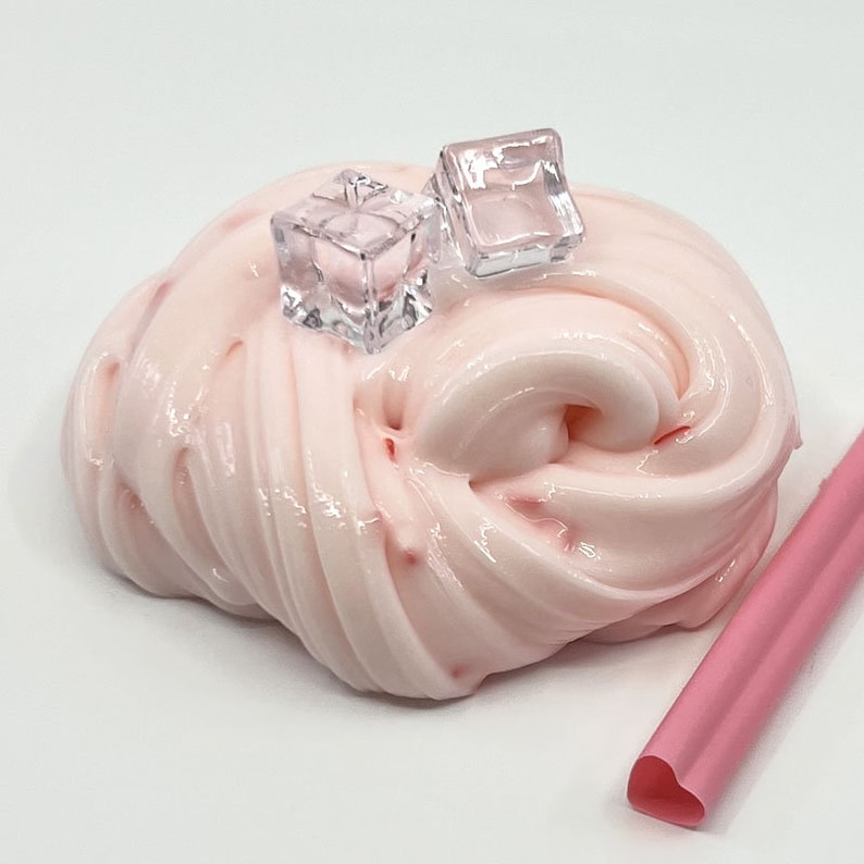 May include: Pink slime with red flecks, topped with two clear plastic ice cubes. A pink heart-shaped straw is in the background.