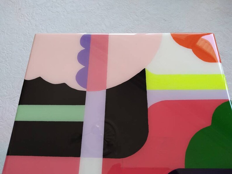 Op de afbeelding: Abstracte geometrische kunstprint met een kleurenschema in roze, zwart, groen, wit, oranje en paars. De print bevat een verscheidenheid aan vormen en patronen.