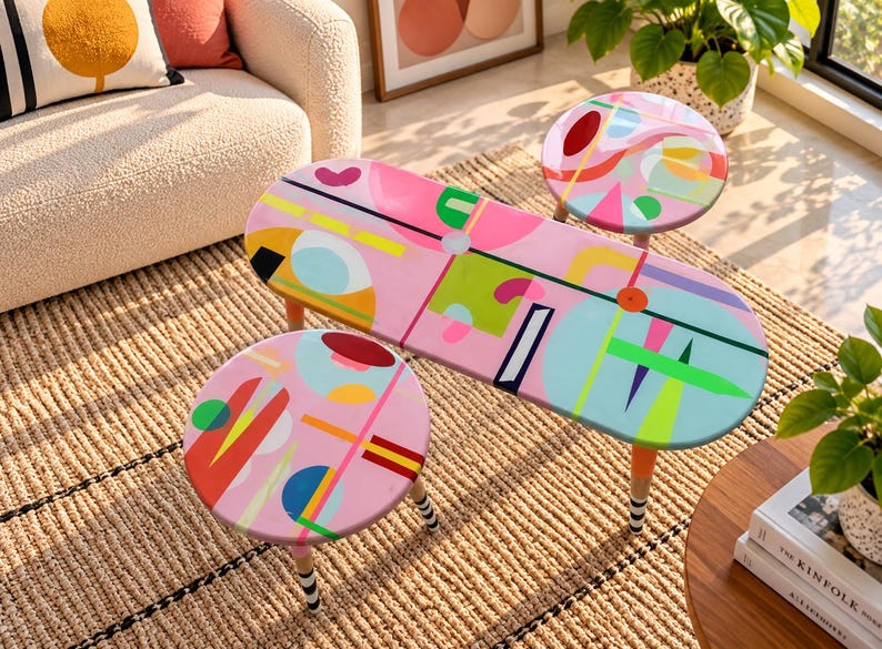 Hand painted colorful round and oval resin side tables with abstract geometric artwork and painted wooden legs in a modern living room.