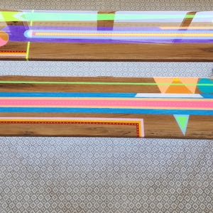 Könnte beinhalten: Zwei Holzbänke mit farbenfrohen geometrischen Designs. Die Bänke haben eine natürliche Holzmaserung mit bemalten Formen in Neon-Grün, Rosa, Blau und Orange. Die Beine sind in Komplementärfarben lackiert.