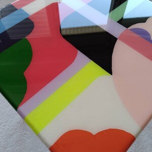 Op de afbeelding: Abstract geometrisch kunstwerk met een glanzende afwerking. Het kunstwerk bevat een verscheidenheid aan kleuren, waaronder roze, groen, geel, wit en zwart. De kleuren zijn gerangschikt in een modern en abstract ontwerp.