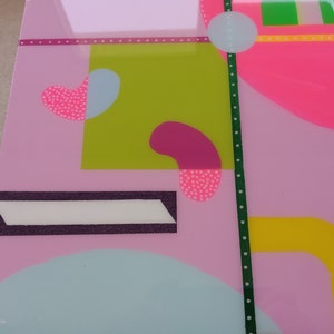 May include: Abstract geometric art print with pink, green, yellow, and blue shapes. The print features a white polka dot pattern on some of the shapes.