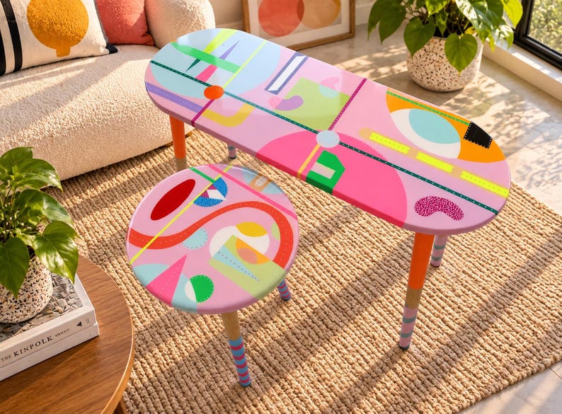 Hand painted colorful round and oval resin side tables with abstract geometric artwork and wooden legs in a modern living room.