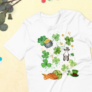 May include: White t-shirt featuring a St. Patrick's Day design. The design includes green shamrocks, a pot of gold, a green hat, and other festive elements. The shirt is made of a soft material and is suitable for casual wear.