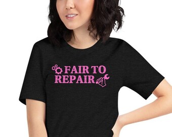 May include: Black t-shirt featuring the pink text "FAIR TO REPAIR" with a gear and wrench graphic. The shirt has a crew neck and short sleeves.