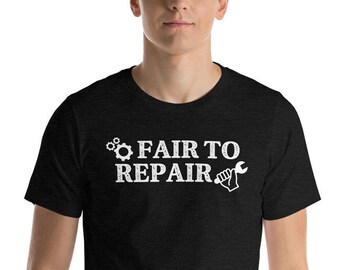 May include: Black t-shirt featuring the white text "FAIR TO REPAIR". The design incorporates a gear, the text, and a wrench graphic. The shirt has short sleeves and is likely made from a soft fabric.