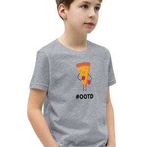 Puede incluir: Una camiseta gris con una porción de pizza de dibujos animados con guantes de boxeo. El texto "#OOTD" está impreso debajo del gráfico de la pizza. La camiseta la lleva una persona con vaqueros.