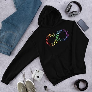 May include: Black hoodie with a colorful infinity symbol design. The symbol is made of small, multi-colored circles. The hoodie has a hood and a front pocket. A pair of blue jeans, sneakers, headphones, and a phone are also in the image.
