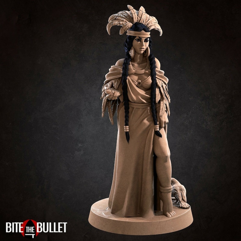 May include: A detailed figurine of a woman wearing a feathered headdress and a long flowing gown. She has long black braids and is holding a small object in her hand. The figurine is painted in shades of brown and black.