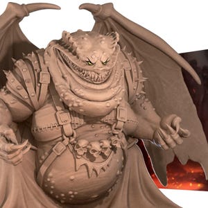 May include: A detailed sculpture of a grotesque demon with large wings, sharp teeth, and a menacing expression. The figure is adorned with armor, straps, and a belt featuring skull accents. The overall color is a muted brown.
