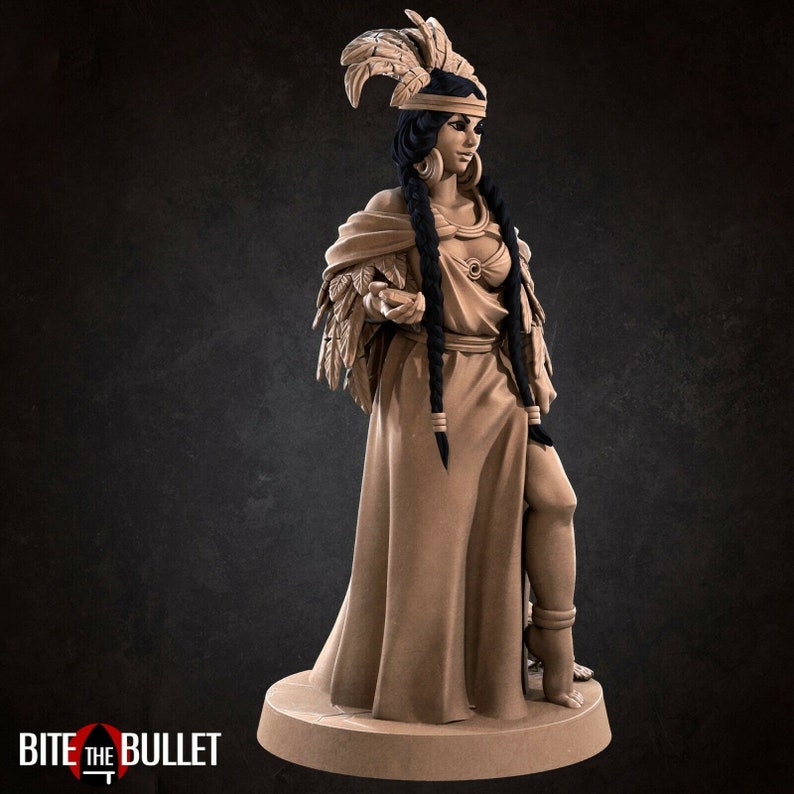 May include: A brown painted figurine of a woman wearing a long dress and a headdress with feathers. She is holding a small object in her hand.