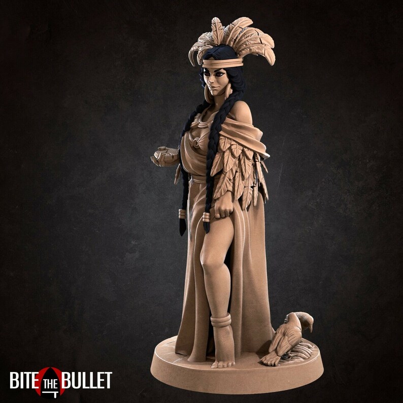 May include: A detailed figurine of a woman wearing a feathered headdress and a long flowing gown. She is holding a small object in her hand and a bird is at her feet.