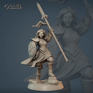 May include: A grey plastic miniature figurine of a female warrior holding a spear and shield. She is wearing armour and a flowing cloak. The figurine is standing on a rocky base.