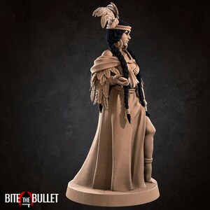 May include: A detailed figurine of a woman wearing a feathered headdress and a long flowing gown. She is holding a small object in her hand. The figurine is made of a light brown material and is painted in a realistic style.