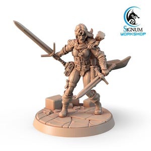Może przedstawiać: Miniaturowa figurka wojowniczki z mieczem w każdej ręce. Jest ubrana w skórzaną zbroję i płaszcz. Figurka stoi na kamiennej podstawie.
