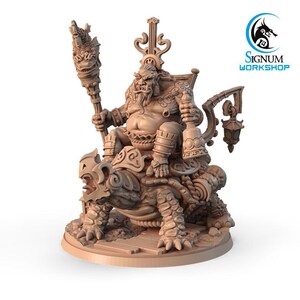 May include: A detailed miniature figurine of a large, round, brown-skinned figure with a beard, wearing a crown and ornate clothing, riding a turtle with a lantern attached to the side. The figure is holding a staff with a dragon head on top. The figurine is made of a light brown material and is set on a round base.