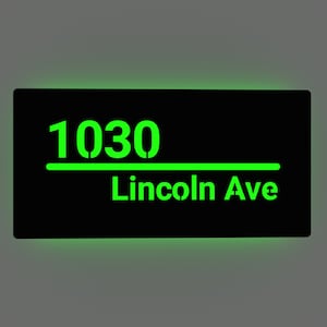 Puede incluir: Un letrero negro con letras verdes que brillan en la oscuridad. El letrero dice "1030 Lincoln Ave".