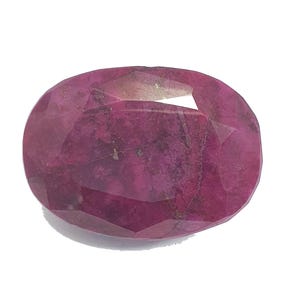 Może przedstawiać: Fasetowany, owalny kamień szlachetny rubinu. Klejnot ma głęboki, bogaty czerwony kolor z widocznymi wtrąceniami wewnętrznymi. Szlif kamienia odsłania wiele faset, tworząc grę światła i cienia. Rubin jest umieszczony na gładkim, białym tle.