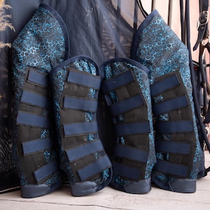 May include: Four blue and black horse leg wraps with a leopard print design. The wraps have multiple velcro straps.