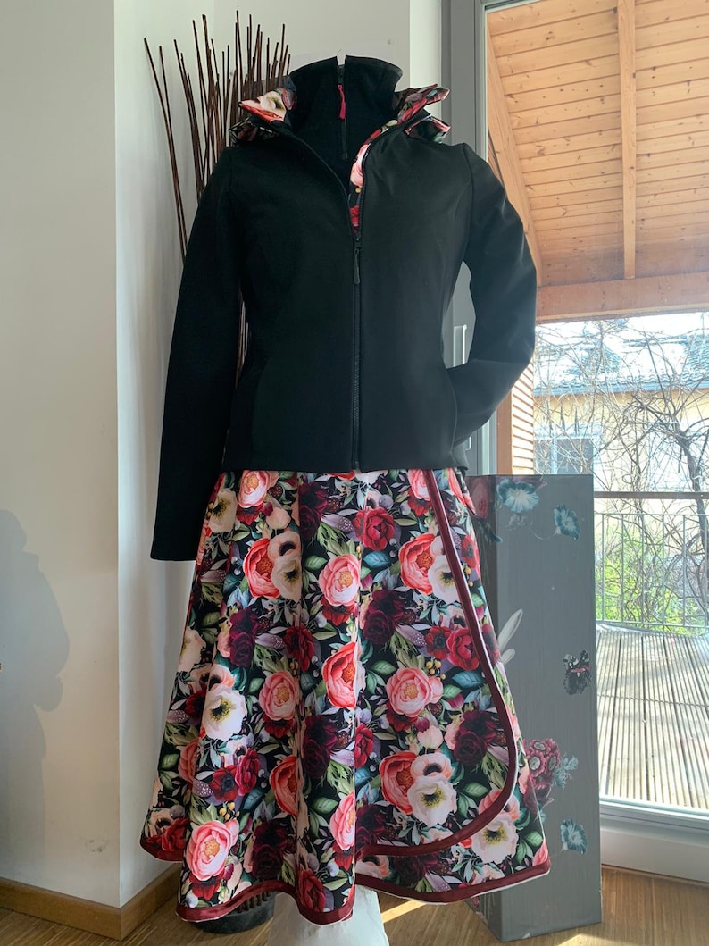 Puede incluir: Una chaqueta negra con forro de estampado floral y una falda floral a juego. La falda tiene un ribete burdeos.