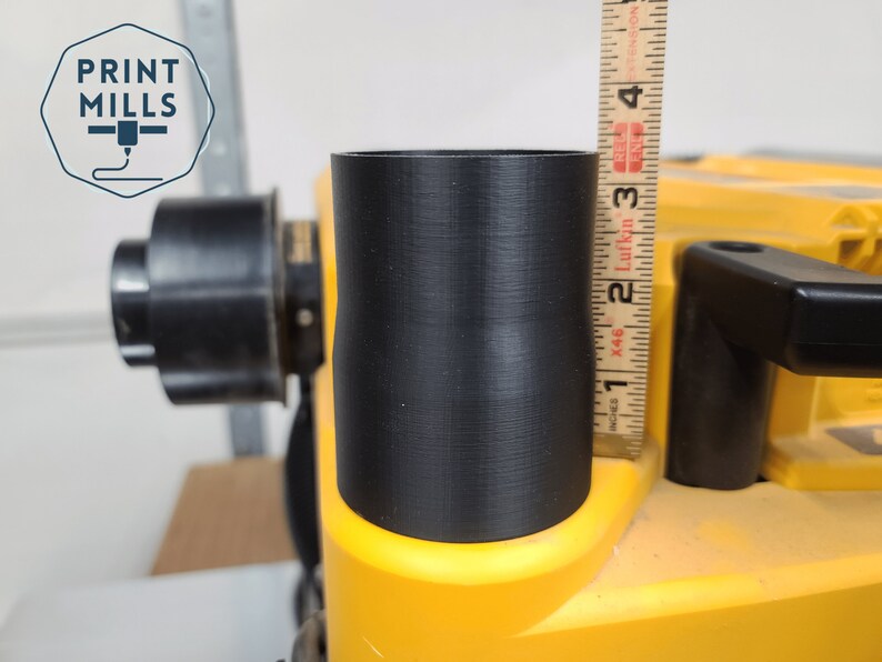 May include: A close-up of a black 3D printed dust collection adapter for a table saw. The adapter is 7.6 cm tall and is being measured with a ruler.