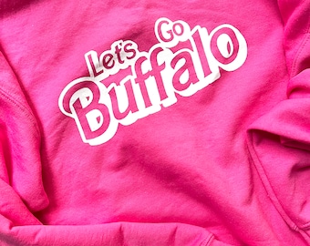 May include: Pink sweatshirt with white text that reads "Let's Go Buffalo".