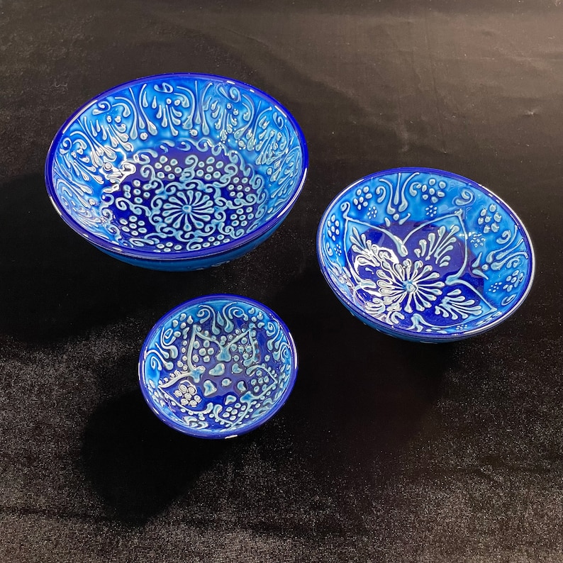 Puede incluir: Tres cuencos de cer&aacute;mica azul y blanca con intrincados dise&ntilde;os florales. Los cuencos est&aacute;n anidados, con el cuenco m&aacute;s grande en la parte superior y el m&aacute;s peque&ntilde;o en la parte inferior.