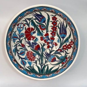 Pode incluir: Uma tigela de cerâmica branca com um desenho floral azul e vermelho. A tigela apresenta um padrão turco tradicional com detalhes intrincados.