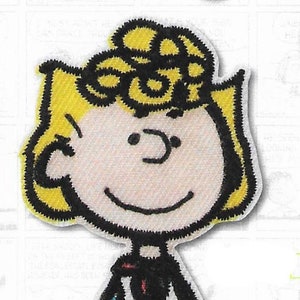 Könnte beinhalten: Ein gestickter Aufnäher mit einer Comicfigur mit blonden Haaren, die ein schwarz-weiß gestreiftes Hemd und eine grüne Hose trägt. Die Figur lächelt und hat einen schwarzen Umriss.