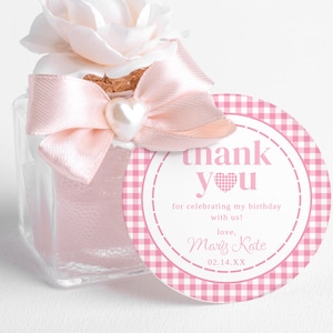 Puede incluir: Etiqueta de favor de vichy rosa y blanco con el texto "thank you" y un corazón rosa. La etiqueta también incluye el texto "for celebrating my birthday with us! love, Mary Kate 02.14.XX"
